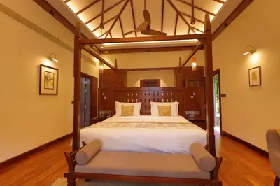 a bedroom with a large bed and two chairs at Taj Wayanad Resort & Spa, Kerala in Wayanad
