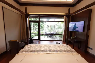 a bedroom with a large bed and a large window at Taj Wayanad Resort & Spa, Kerala in Wayanad