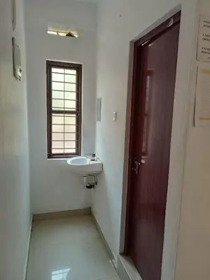a bathroom with a sink and a wooden door at KK Residency in Perintalmanna