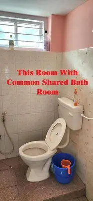 a bathroom with a toilet and a sign on the wall at JJ's White House in Trichūr