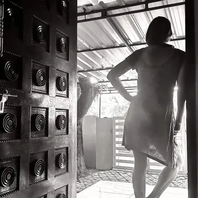 a woman is standing in front of a door at JJ's Holiday Home in Thanniyam