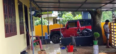 a man standing next to a red truck in a garage at JJ's Holiday Home in Thanniyam