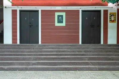 a red building with three doors and stairs in front at Deepwoods Stay-Kinathukadavu, Coimbatore in Coimbatore