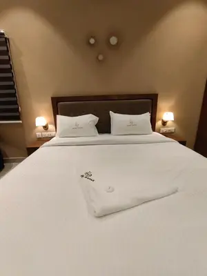 a white bed with two white pillows on it at Hotel PSY in Mettuppālaiyam