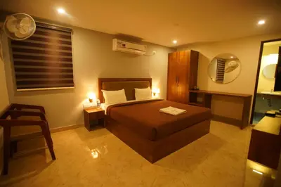 a bedroom with a bed and a table and a chair at Hotel PSY in Mettuppālaiyam