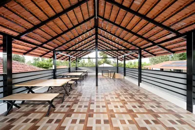 a pavilion with tables and benches on a wooden floor at Hatti Eden Coorg in Gonikoppal