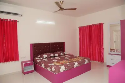 a bedroom with a bed with red curtains and a fan at The best villa stay- family friendly in Coimbatore