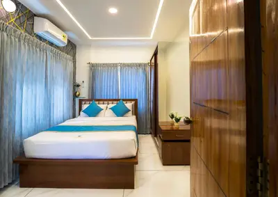 a bedroom with a bed with blue curtains at Royal Tusker Luxury Service Apartments in Mysore