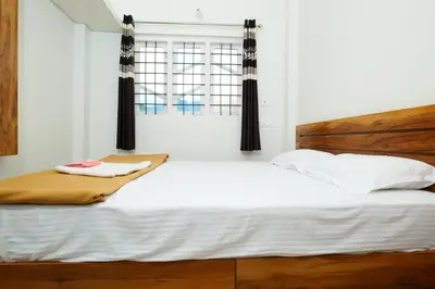 a bedroom with a large white bed and a window at Hillside Hideaway Gudalur in Gūdalūr