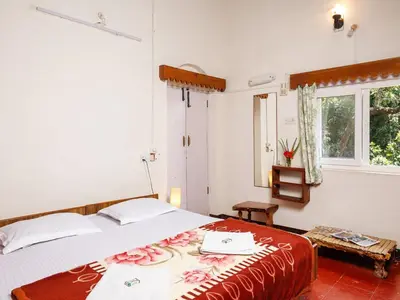 a bedroom with a large bed and a window at DEVASHOLA HOMESTAY in Coonoor