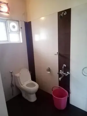 a bathroom with a toilet and a window and a shower at New Hill Valley Family Homestay-WiFi-View in Madikeri