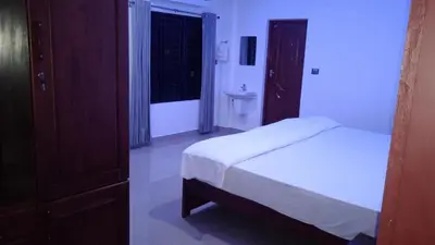 a bedroom with a bed and a bathroom with a window at Mscb guest house in Idukki