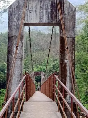 a person walking across a bridge over a river at Mscb guest house in Idukki
