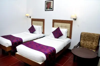 a hotel room with two beds and a chair at BROAD BEAN Chakkarakkal in Chakkarakkal