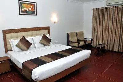 a hotel room with a large bed and a chair at BROAD BEAN Chakkarakkal in Chakkarakkal