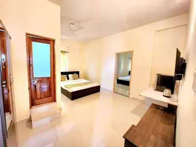 a large room with a bed and a mirror at Suyog Apartments in Mysore