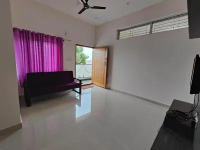 a living room with a couch and a window at Suyog Apartments in Mysore