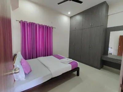 a bedroom with a bed with a purple curtain at Suyog Apartments in Mysore