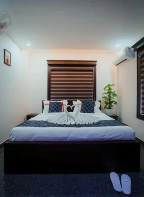 a bedroom with a large bed with a wooden headboard at BEVERLY SUITES in Wayanad