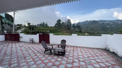 two chairs and a table on a patio with a view at ATTUVAM VISTA in Kodaikānāl