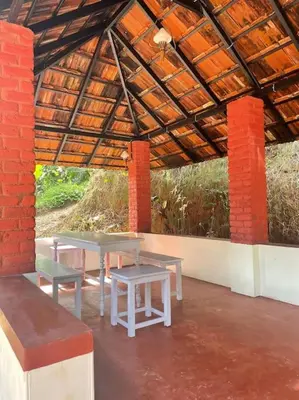a patio with tables and benches in a building at Deesha Homes in Wayanad