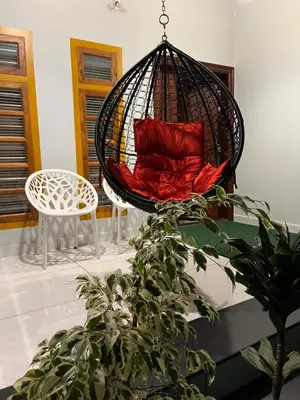a swing with two red pillows in a room at Milaano Orchids, Service Villa, Kammana Mananthavady in Wayanad