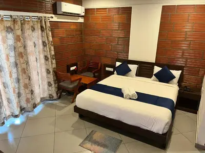 a bedroom with a large bed with blue and white sheets at Coorg Vismaya in Madikeri