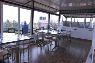 a group of tables and chairs in a room with windows at Cloud Nine Kothagiri By Lexstays in Kotagiri