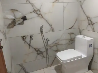 a bathroom with a toilet with marble walls at Malapuram quarters in Malappuram