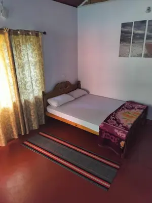 a small bedroom with a bed and a window at Madan Homestay in Napoklu