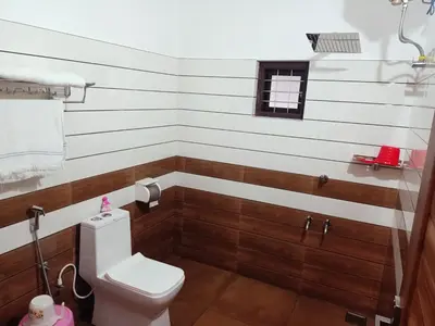 a bathroom with a white toilet and wooden floors at Divine View Holyday Home (Homestay) in Kalpetta