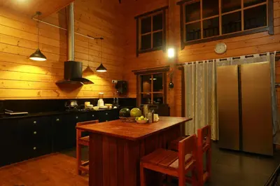 a kitchen with a table with chairs and a refrigerator at amã Stays & Trails The Malabar Villa Heliconia, Kozhikode in Wayanad