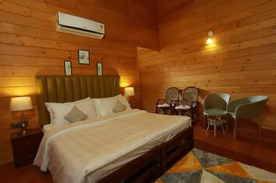 a bedroom with a bed and a table and chairs at amã Stays & Trails The Malabar Villa Heliconia, Kozhikode in Wayanad