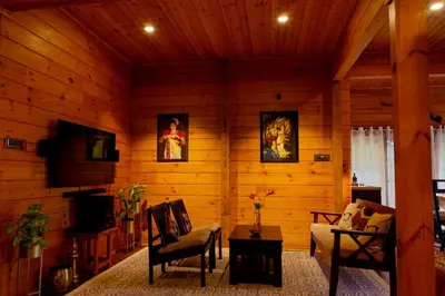 a living room with wood paneling and a couch and chairs at amã Stays & Trails The Malabar Villa Heliconia, Kozhikode in Wayanad