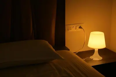 a bedroom with a bed with a lamp next to it at Royad Calicut Farm House - Premium Villa with Pool Inside a Farm in Kozhikode