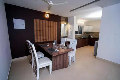 a dining room with a wooden table and white chairs at Lantern Apart Hotel in Perintalmanna