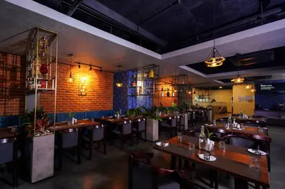 a restaurant with wooden tables and chairs and a brick wall at Lantern Apart Hotel in Perintalmanna