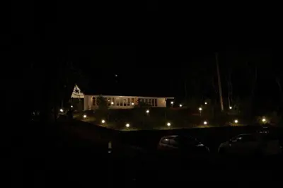 a house at night with cars parked in front of it at Fortune Clio Resort in Periya