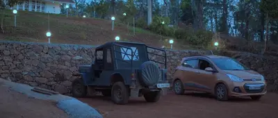 a small car parked next to a stone wall at Fortune Clio Resort in Periya