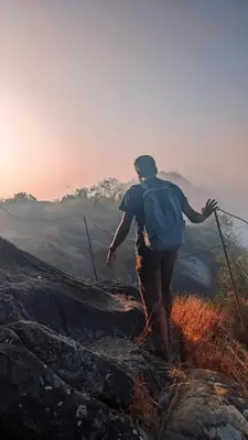 a man with a backpack standing on top of a mountain at Crossroads Hostel 1957 in Wayanad
