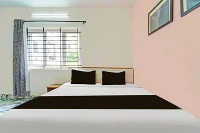 a bedroom with a large bed and a window at Super Hotel O Vijaynagar Road Formerly Anmol Peace Stay in Ooty