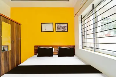 a bedroom with yellow walls and a bed with two pillows at Super Hotel O Vijaynagar Road Formerly Anmol Peace Stay in Ooty