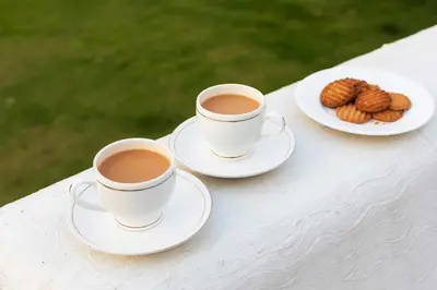two cups of coffee and a plate of cookies on a table at StayVista at The Alcove with Breakfast & BBQ Grill in Ooty