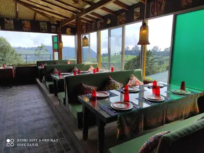 a dining room with tables and chairs and windows at Habba Kadal Kashmiri Heritage Hotel & Hub in Coonoor