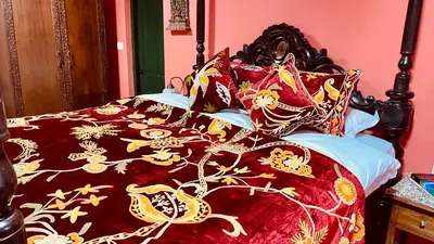 a bed with a red and gold blanket and pillows at Habba Kadal Kashmiri Heritage Hotel & Hub in Coonoor