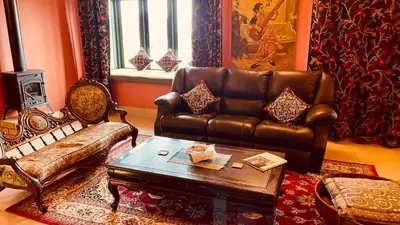 a living room with a leather couch and a coffee table at Habba Kadal Kashmiri Heritage Hotel & Hub in Coonoor