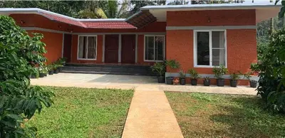 a red house with a pathway in front of it at FernHills Homestay in Madikeri