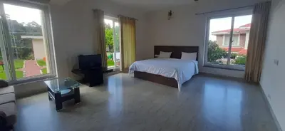 a bedroom with a bed and a tv and windows at Velus Bungalow Ooty in Ooty
