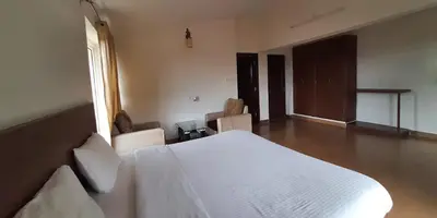 a bedroom with a white bed and a window at Velus Bungalow Ooty in Ooty