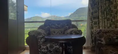 a chair with a table in front of a window at Velus Bungalow Ooty in Ooty